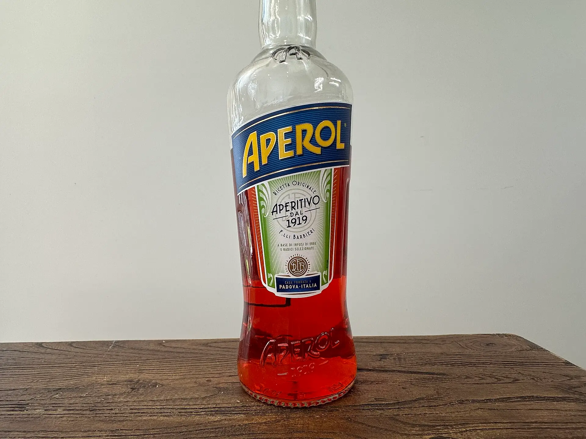 An Aperol bottle on a wooden table — the orange aperitivo every Ligurian seaside bar pours at sunset.